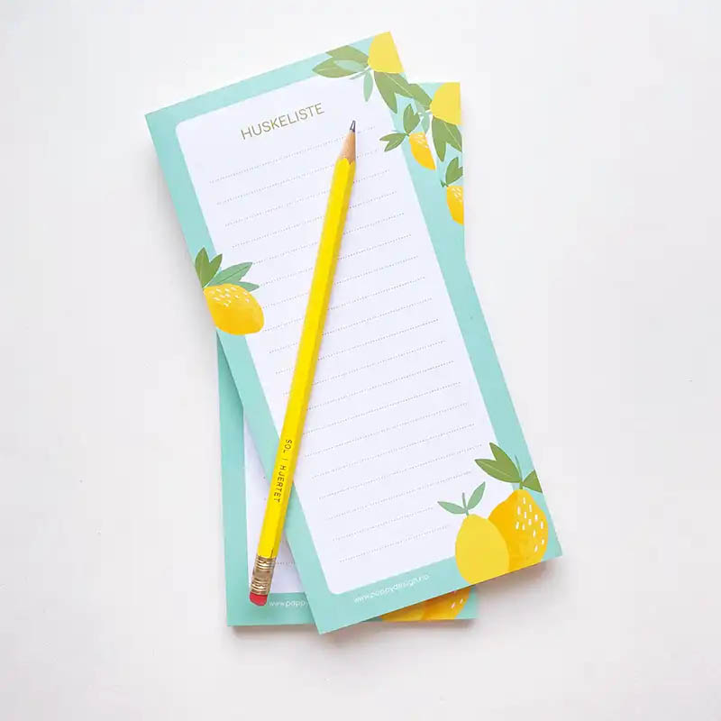 bilde av en notatblokk med turkis kant og sitrondekor. På toppen ligger det en gul blyant.