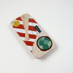 Metallboks med en dame på stranden og en kurv full av garn